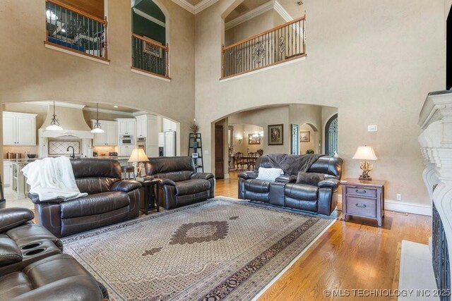 716 W 108th Pl S, Jenks, OK 74037 - living room with arched walkways, crown molding, light wood-style flooring, a high ceiling, and baseboards