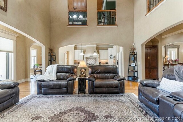 716 W 108th Pl S, Jenks, OK 74037 - living room with arched walkways, a towering ceiling, light wood-style floors, and healthy amount of natural light