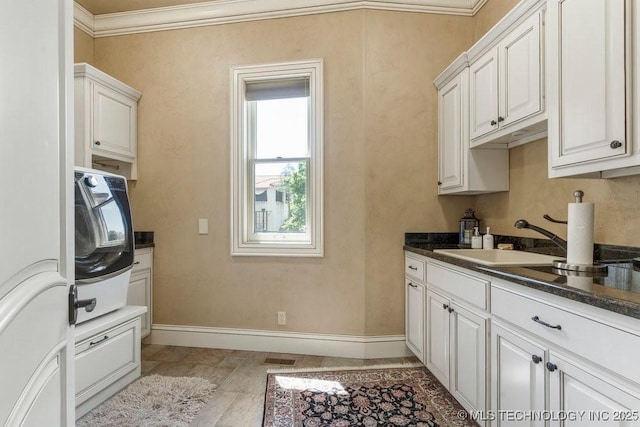 716 W 108th Pl S, Jenks, OK 74037 - kitchen with dark countertops, ornamental molding, baseboards, white cabinets, and a sink