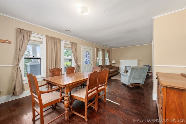 dining area with dark wood-type flooring, a fireplace, crown molding, and baseboards