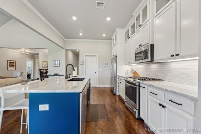 kitchen with stainless steel appliances, a sink, ornamental molding, open floor plan, and decorative backsplash
