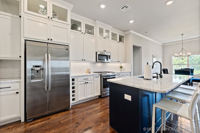 kitchen with stainless steel appliances, a sink, ornamental molding, white cabinets, and decorative backsplash