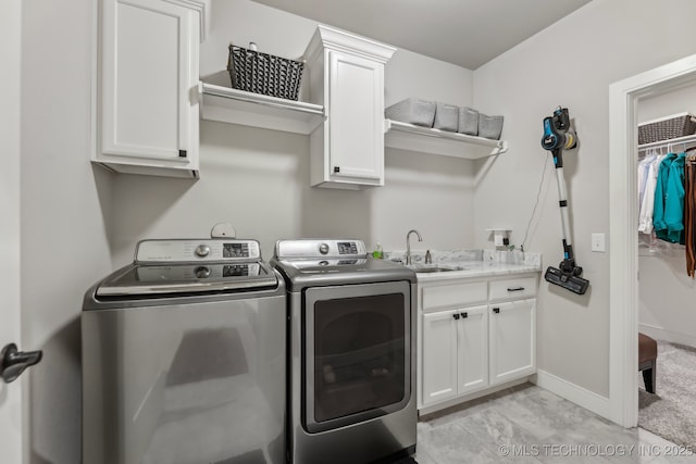 washroom with separate washer and dryer, cabinet space, light marble finish floors, and baseboards
