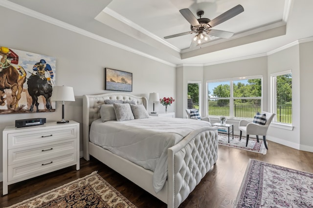 bedroom with a raised ceiling, dark wood-style floors, ornamental molding, and baseboards