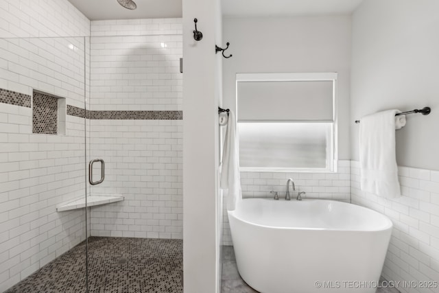bathroom featuring a stall shower, a freestanding bath, and tile walls