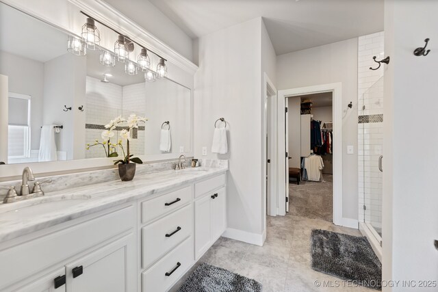 bathroom with a stall shower, a spacious closet, double vanity, baseboards, and tile patterned flooring