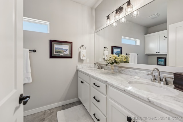 full bath with healthy amount of natural light, double vanity, and baseboards