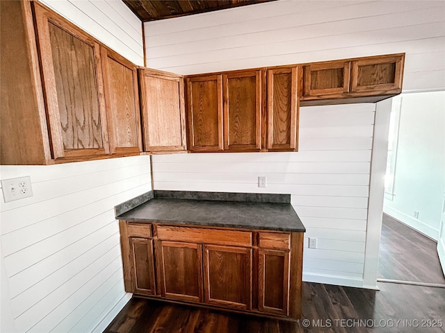 216 Belt Ave, Eufaula, OK 74432 - kitchen with dark countertops, dark wood-style flooring, brown cabinetry, and wooden walls