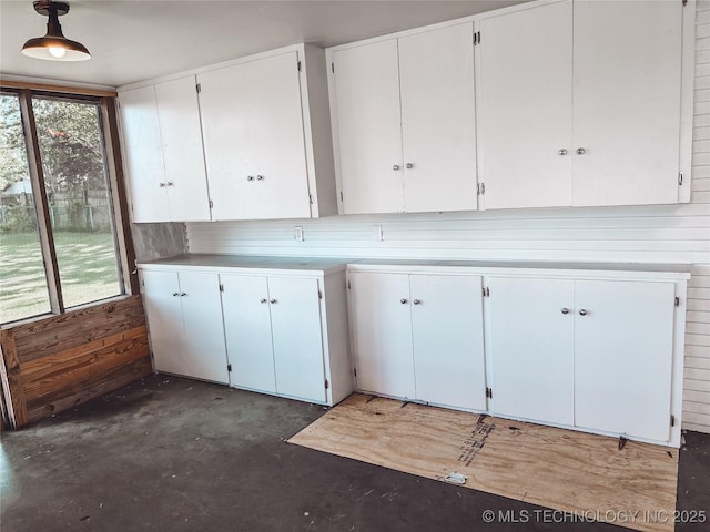 216 Belt Ave, Eufaula, OK 74432 - kitchen featuring unfinished concrete floors, plenty of natural light, light countertops, white cabinets, and wood walls