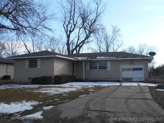 single story home featuring an attached garage, driveway, and central air condition unit