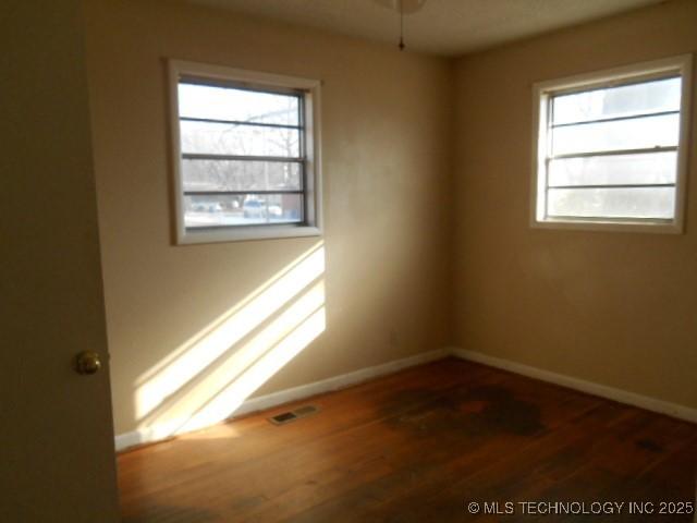 empty room featuring baseboards, plenty of natural light, and wood finished floors