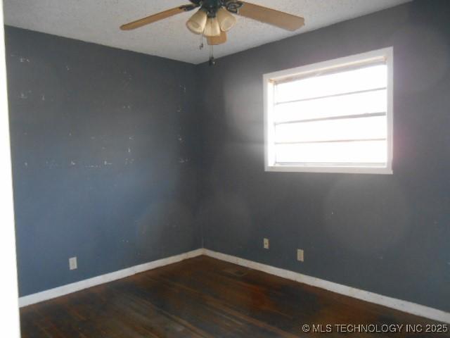 empty room featuring a ceiling fan, wood finished floors, and baseboards