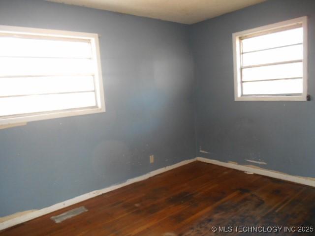 empty room featuring dark wood-type flooring and baseboards