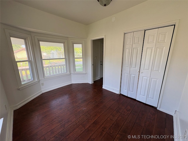 108 N Creek Ave, Bartlesville, OK 74003 - unfurnished bedroom with dark wood-style floors, multiple windows, baseboards, and a closet