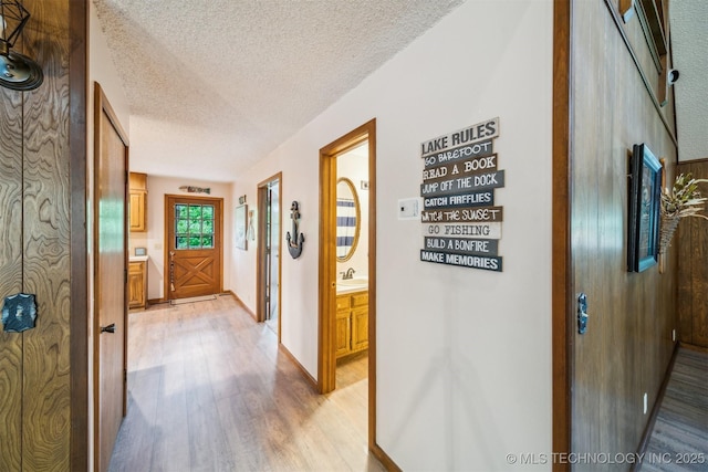 205 Woods Dr, Bernice, OK 74331 - hallway with light wood-style floors, a textured ceiling, a sink, and baseboards
