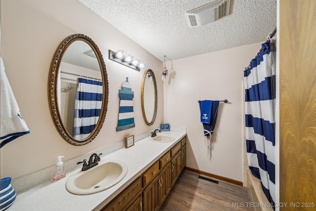 205 Woods Dr, Bernice, OK 74331 - bathroom featuring a textured ceiling, wood finished floors, curtained shower, and double vanity