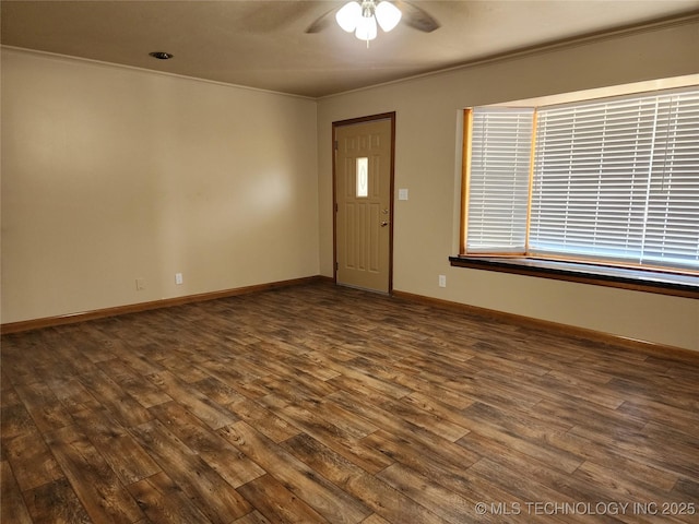 spare room with dark wood-style floors, a ceiling fan, ornamental molding, and baseboards