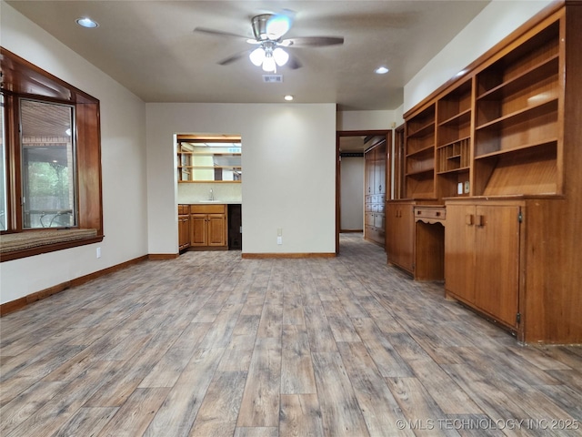 unfurnished living room featuring a ceiling fan, light wood finished floors, baseboards, recessed lighting, and a sink