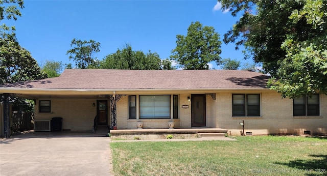 ranch-style house featuring concrete driveway, brick siding, a carport, and a front lawn