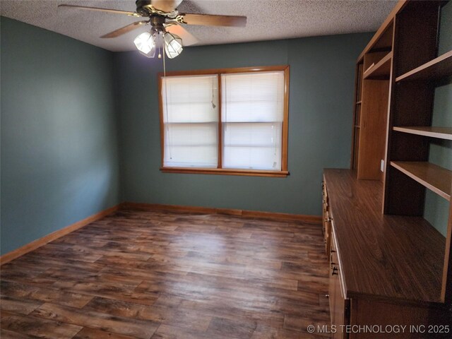 spare room featuring a textured ceiling, dark wood-style flooring, ceiling fan, and baseboards