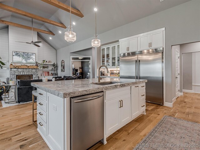 13606 S 21st Pl E, Bixby, OK 74008 - kitchen with stainless steel appliances, a sink, beamed ceiling, an island with sink, and light wood-style floors