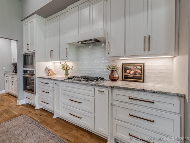 13606 S 21st Pl E, Bixby, OK 74008 - kitchen with appliances with stainless steel finishes, light wood-style flooring, white cabinetry, and tasteful backsplash