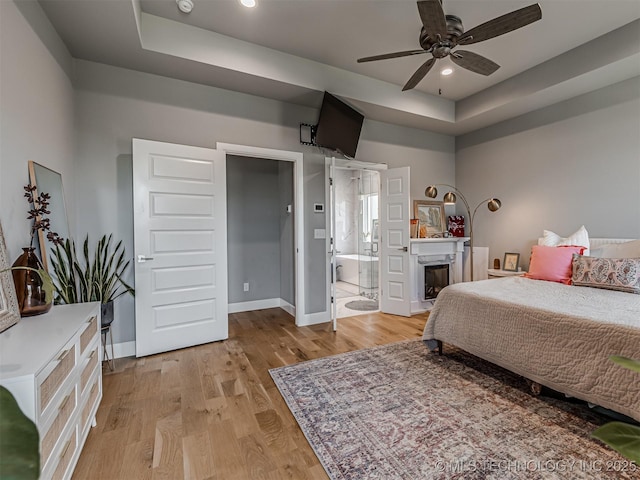 13606 S 21st Pl E, Bixby, OK 74008 - bedroom featuring light wood finished floors, baseboards, a raised ceiling, a fireplace, and recessed lighting