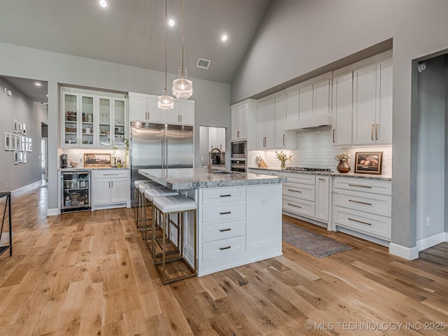 13606 S 21st Pl E, Bixby, OK 74008 - kitchen with beverage cooler, built in appliances, high vaulted ceiling, light wood-style floors, and tasteful backsplash