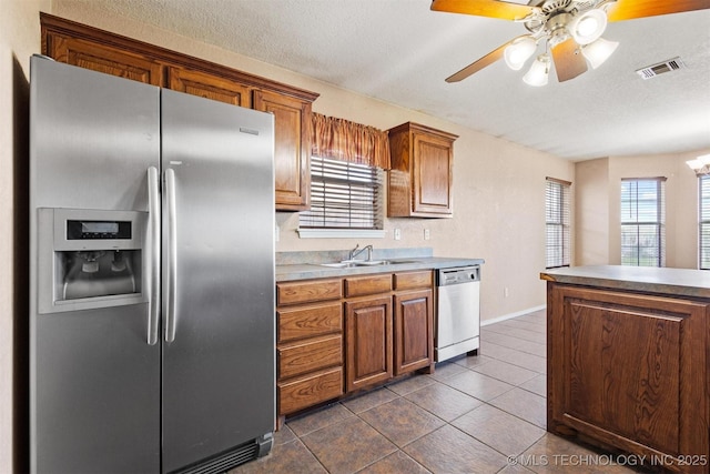 205 Summit, Durant, OK 74701 - kitchen featuring appliances with stainless steel finishes, a sink, plenty of natural light, brown cabinets, and a textured ceiling