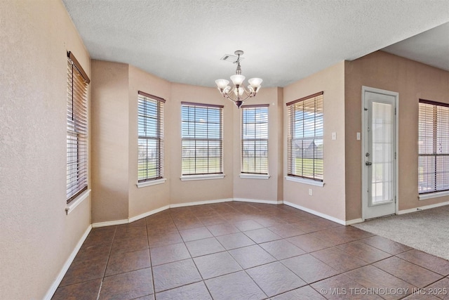 205 Summit, Durant, OK 74701 - unfurnished dining area with dark tile patterned flooring, a chandelier, healthy amount of natural light, a textured ceiling, and baseboards
