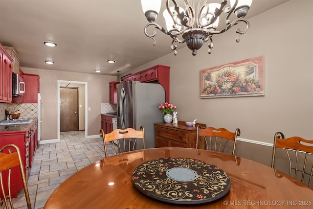 dining room with stone tile floors, a chandelier, recessed lighting, and baseboards