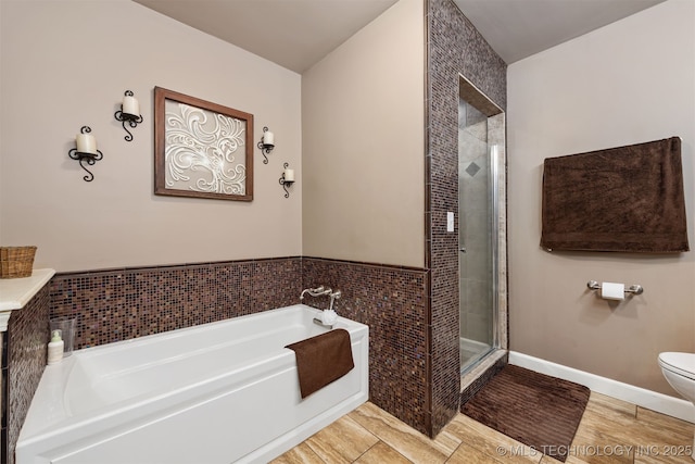 full bathroom with a shower stall, tile walls, a garden tub, toilet, and wood finished floors