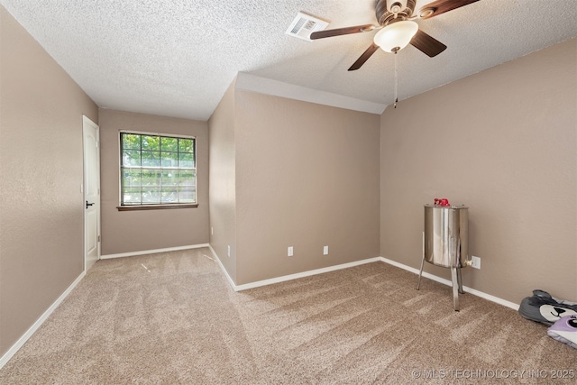 carpeted spare room featuring ceiling fan, a textured ceiling, and baseboards