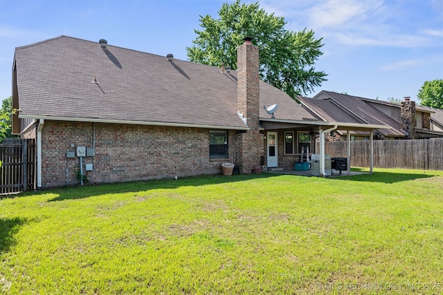 rear view of house with a patio area, brick siding, a shingled roof, and a chimney