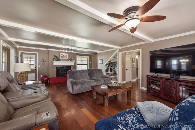 living area featuring wood-type flooring, a fireplace with raised hearth, beamed ceiling, ceiling fan, and plenty of natural light