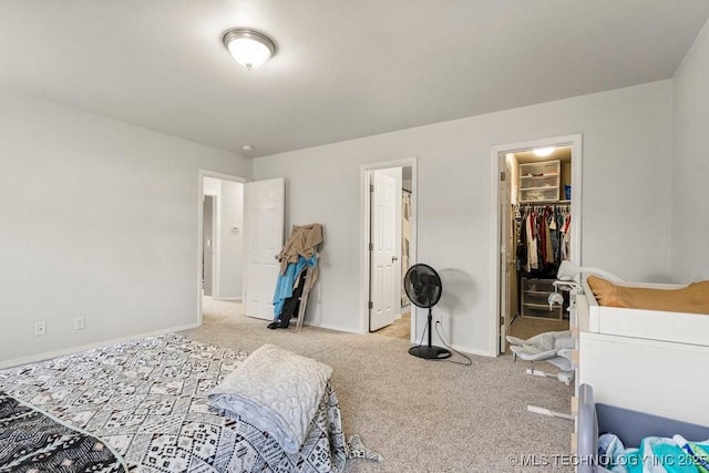 carpeted bedroom featuring baseboards, a walk in closet, and a closet