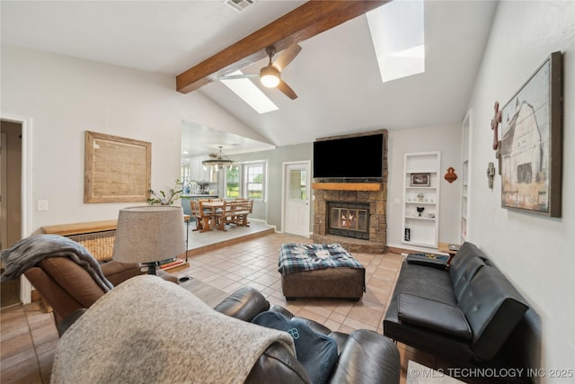 tiled living room featuring a skylight, a ceiling fan, and a stone fireplace