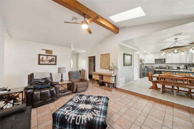 living area with light tile patterned floors, ceiling fan, a skylight, and baseboards