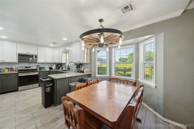 kitchen with stainless steel appliances, a sink, decorative backsplash, white cabinetry, and light stone countertops