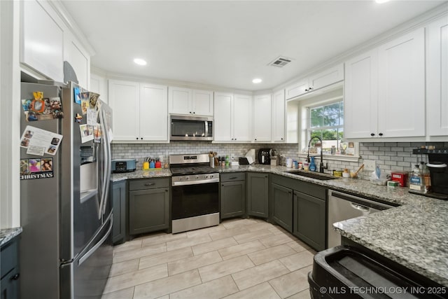kitchen with stainless steel appliances, a sink, decorative backsplash, white cabinetry, and recessed lighting