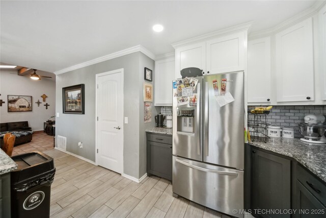 kitchen featuring stainless steel fridge, tasteful backsplash, white cabinetry, light stone countertops, and crown molding