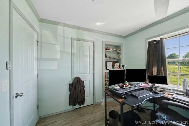 home office with crown molding, built in shelves, and wood finished floors
