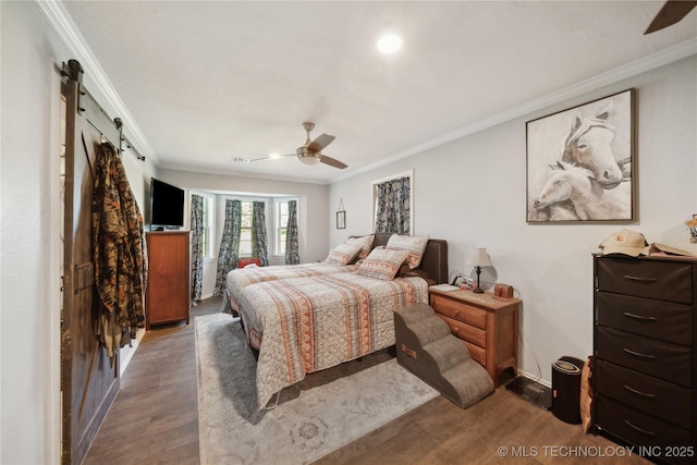 bedroom with wood finished floors, ornamental molding, a barn door, ceiling fan, and baseboards