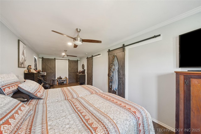 bedroom featuring a barn door, wood finished floors, ornamental molding, baseboards, and a ceiling fan