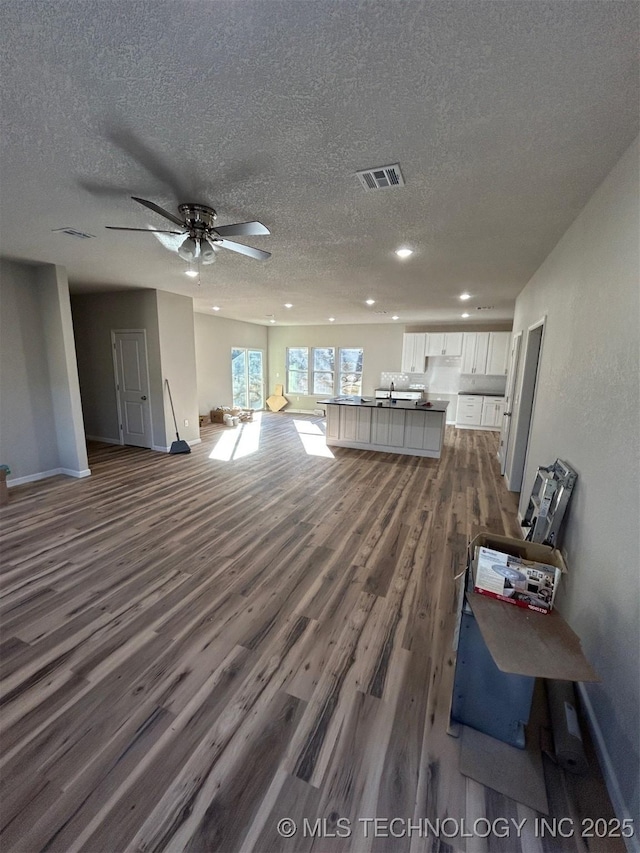 living room featuring dark wood finished floors, baseboards, a textured ceiling, recessed lighting, and a ceiling fan