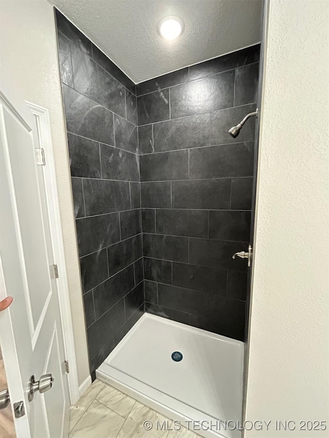 bathroom with marble look tiles, a stall shower, and a textured ceiling