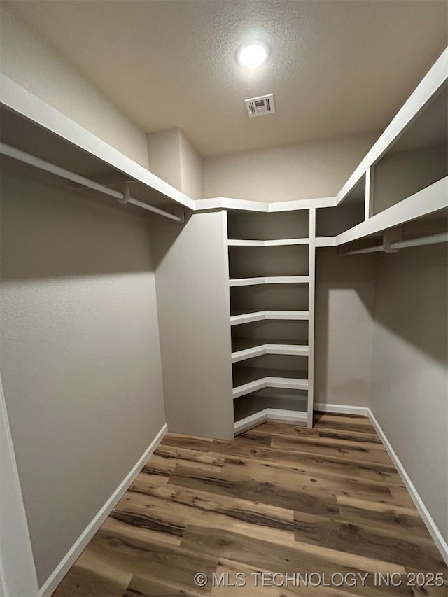 walk in closet with wood finished floors