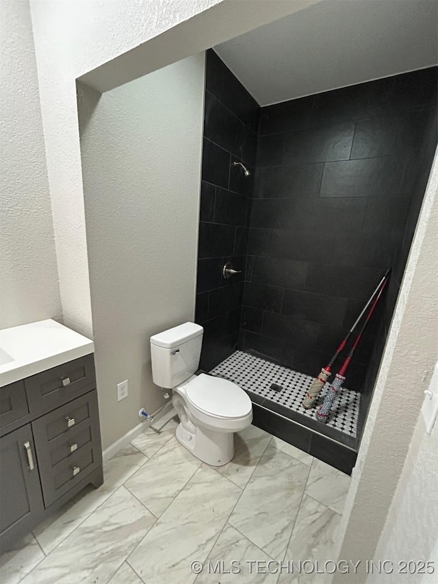 full bathroom featuring marble look tiles, a shower stall, toilet, and vanity