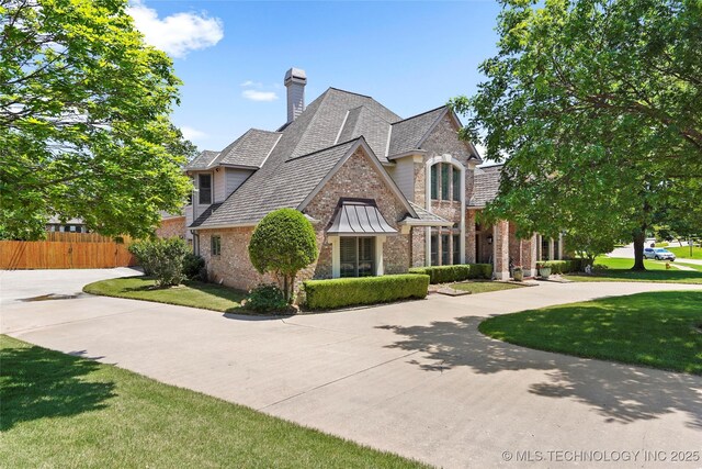 10105 S 72nd E Ave, Tulsa, OK 74133 - french country home with brick siding, a chimney, curved driveway, and roof with shingles