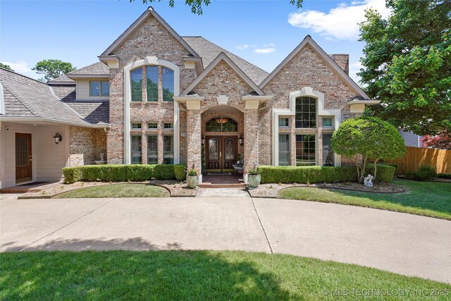 10105 S 72nd E Ave, Tulsa, OK 74133 - french country style house with french doors, brick siding, fence, roof with shingles, and a chimney
